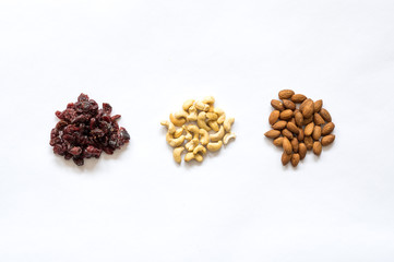 Three heaps of healthy raw food, cranberries, cashew and almonds.