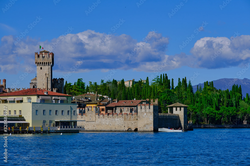 Wall mural Rocca Scaligera Castle in Sirmione Lake Garda, Italy. Boat with tourists on the background of the castle