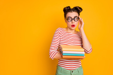 Photo of student lady hold many books look side empty space terrified wear freak nerd specs striped red white shirt green pants isolated bright yellow color background