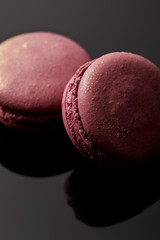 close up view of shiny pink french macaroons on black background