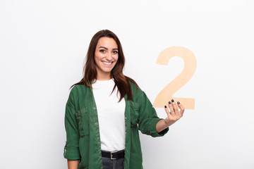 young pretty woman excited, happy, joyful, holding a number 2.