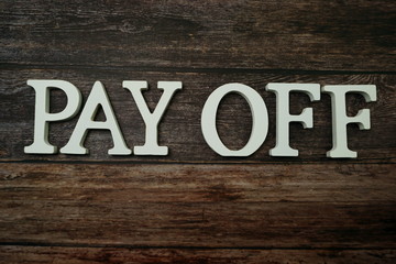 Pay Off alphabet letters on wooden background
