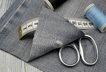 sewing accessories and jeans on wooden background