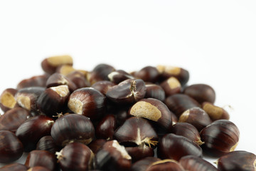 A handful of edible chestnuts separated on a white background. Isolated white background and autumn forest edible brown chestnuts.