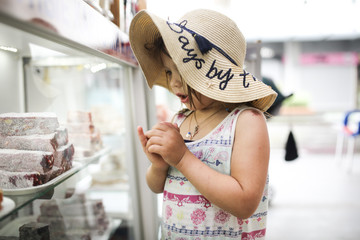child in dress picks and tastes oriental sweets