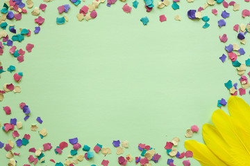 Fototapeta premium Purim carnival green background with colorful confetti and yellow feathers