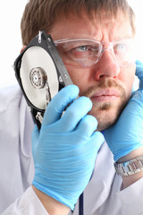 Repairman attached the hard drive of the computer to his ear. Listens to knock and crack reveals...