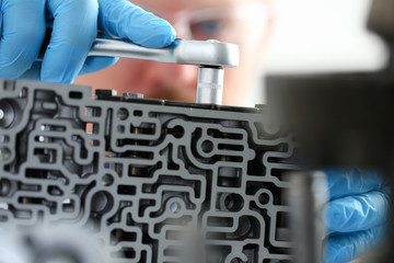 Repairman car-care center on repair of automatic transmissions holds in hand horn key carries out disassembling assemblage hydroblock detail carries diagnostics makes an estimation of working capacity