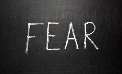 Text FEAR written in white chalk on a black chalkboard