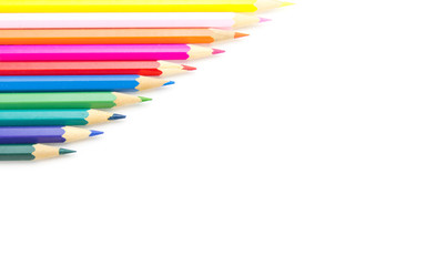 Multicolored wooden sharpened pencils neatly folded with a ladder on a large isolated background in the corner. There is free space for text.