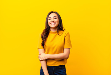 young latin pretty woman laughing shyly and cheerfully, with a friendly and positive but insecure...
