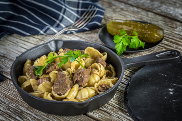Italian pasta shells with beef sauce in cast iron pan.