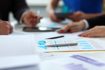 Silver pen lie on important paper at table with group of colleagues in background closeup. Paperwork job trade balance bank credit loan money invest payment irs commerce partnership concept