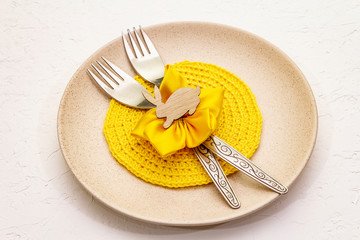 Easter table setting on textured white putty background. Spring holiday card template. Cutlery,...