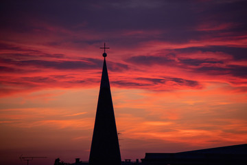 No filter sunset in urban environment, with close up on the bell tower of a catholic church....