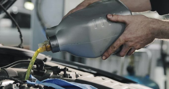 Mechanic's Hands. Engine Oil Flows From The Canister Into The Engine Of A Car.
