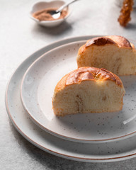 a dessert of a homemade kraffin on a light plate, cinnamon and sugar cane stick on the background
