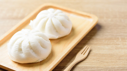Fototapeta na wymiar Steamed buns on wooden plate and fork ready to eating, Asian food