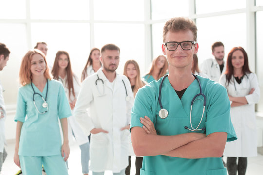 smiling young doctor standing in front of his senior colleagues.