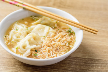 Instant noodles soup and wonton dumpling stuffed with minced pork in a bowl and chopsticks, Asian food
