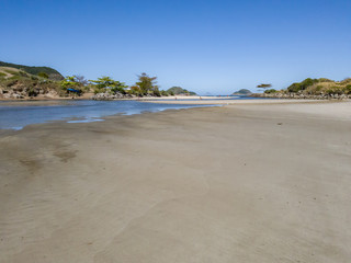 Sunset, golden light, between the sea and the lagoon of Itaipu, where a small beach appears, where surfers have fun. In the background, the profile of the mountains, the city of Rio de Janeiro.