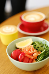Healthy breakfast. Tasty breakfast in a cafe: tomatoes, salmon, cucumber, arugula in a deep blue plate on a wooden table. 