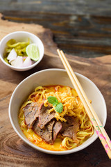 Local Northern Thai food (Khao Soi), spicy curry noodles soup with coconut milk and beef in a bowl with chopsticks