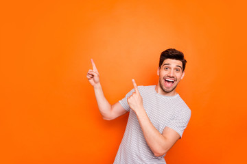 Fototapeta Photo of attractive guy hold hands fingers direct up empty space excited good mood sales person wear striped t-shirt isolated bright orange color background obraz