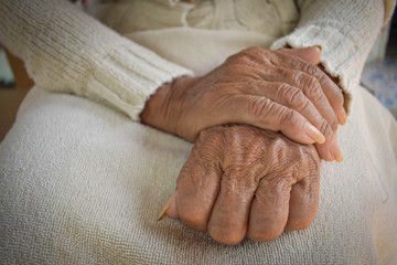  Wrinkled hand of the elderly is placed on the lap