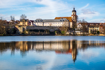 Scenic view of houses by a lake with city walls in the background