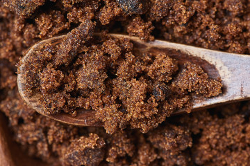 Dark muscovado sugar, also called Barbados sugar, khandsari, or khand, in wooden spoon - obrazy, fototapety, plakaty