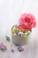 Wafer Paper Flower - Pink  Peony - and colored meringue cookies, on white wooden background.