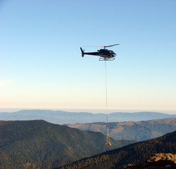 Fototapeta na wymiar Helicopter transports a sawn timber