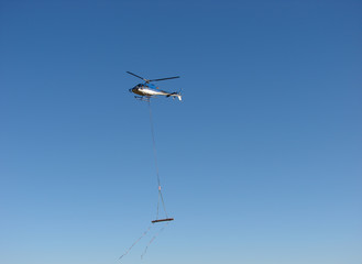 Helicopter transports a wood beam
