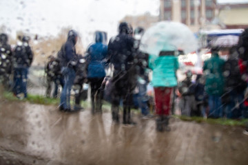 Blurred background. A crowd of people standing in the rain and snow. Autumn, winter weather.