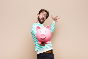 young cool man holding a piggy bank against clean wall