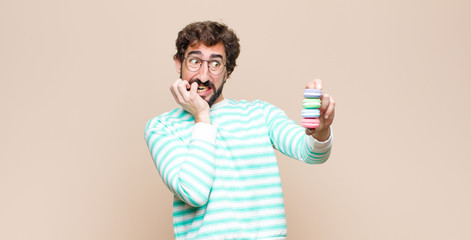young man with macaroons against flat wall