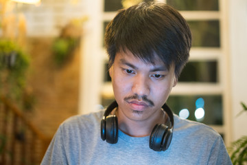 Young man using laptop listening to music on headphone
