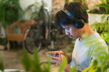 Young man using mobile phone with headphone around his neck