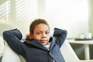 Boy as a manager sits relaxed in a chair