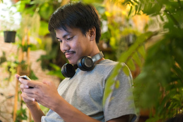 Young man using mobile phone with headphone around his neck