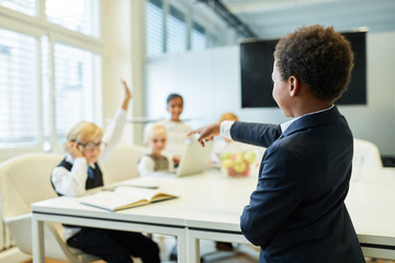 Child as a teacher asks students questions in the classroom