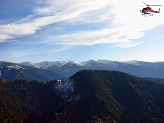 Red Helicopter flying above the mountain