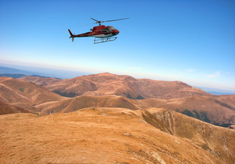 Fototapeta na wymiar Red helicopter above the mountain