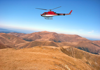 Fototapeta na wymiar Red helicopter above the mountain