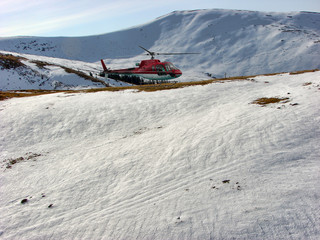 Red helicopter on mountain with snow