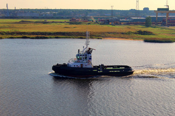 A small old river ship runs along the sea