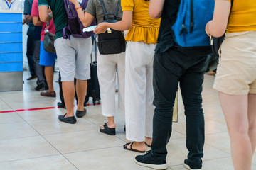Queue of Asian people waiting at boarding gate at airport. Close-up composition
