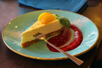 Delicious cherry cheesecake slice with sauce on plate.