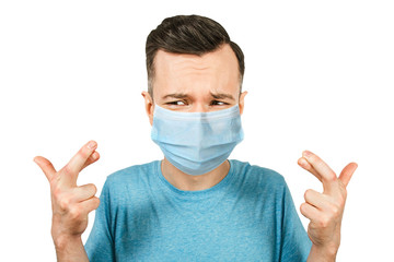 Portrait young man with cross fingers. wearing protective face mask prevent virus infection, white isolated background